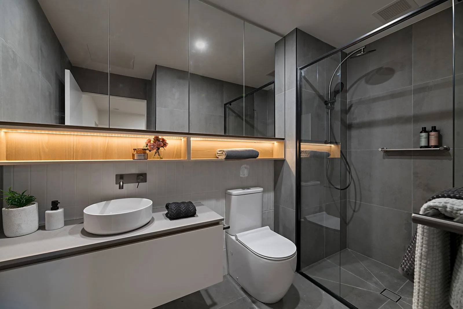 The Elm, Moonee Ponds: stone-tiled bathroom with LED-lit shelf and glass shower